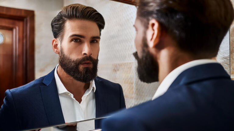 a man checking out his well groomed beard in the mirror.